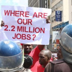 A supporter of the opposition party Movement for Democratic Change (MDC-T) holds placard in front of policemen during a protest against poverty and corruption, in Harare, Zimbabwe, 14 April 2016. Reports state protesters, led by party leader Morgan Tsvangirai, demonstrated against poverty, corruption and the missing of 15 billion US dollars of diamond revenue. Picture: EPA/AARON UFUMELI